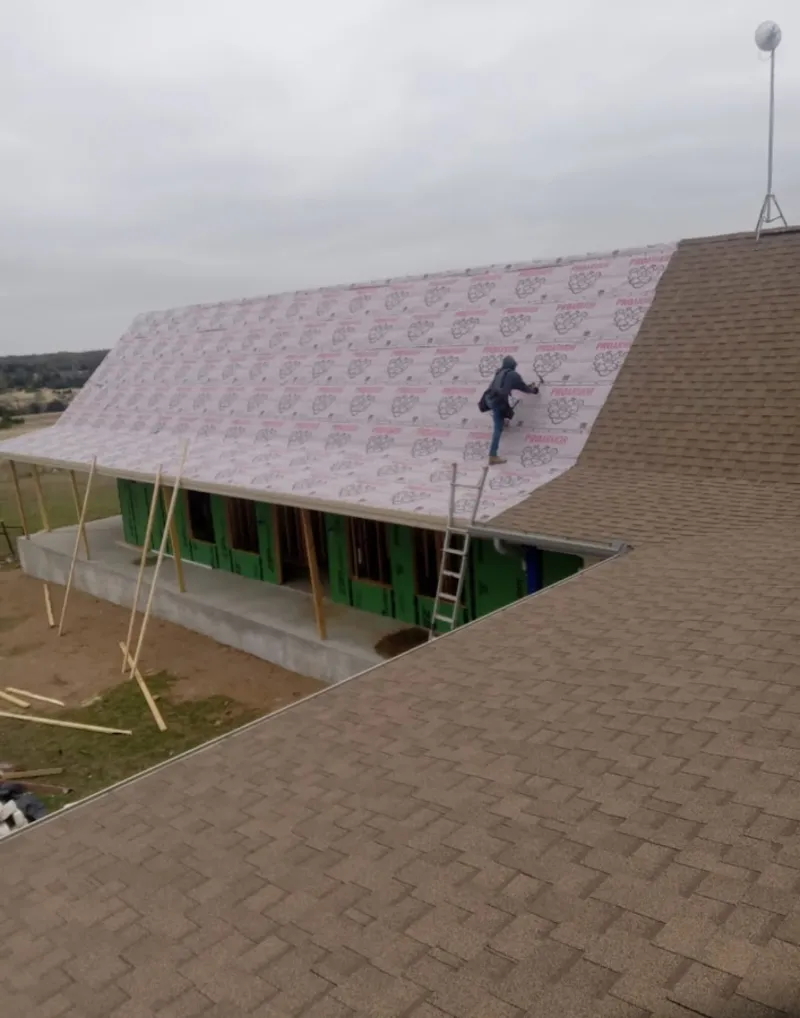 Worker preparing underlayment for a metal roof installation in Wendell